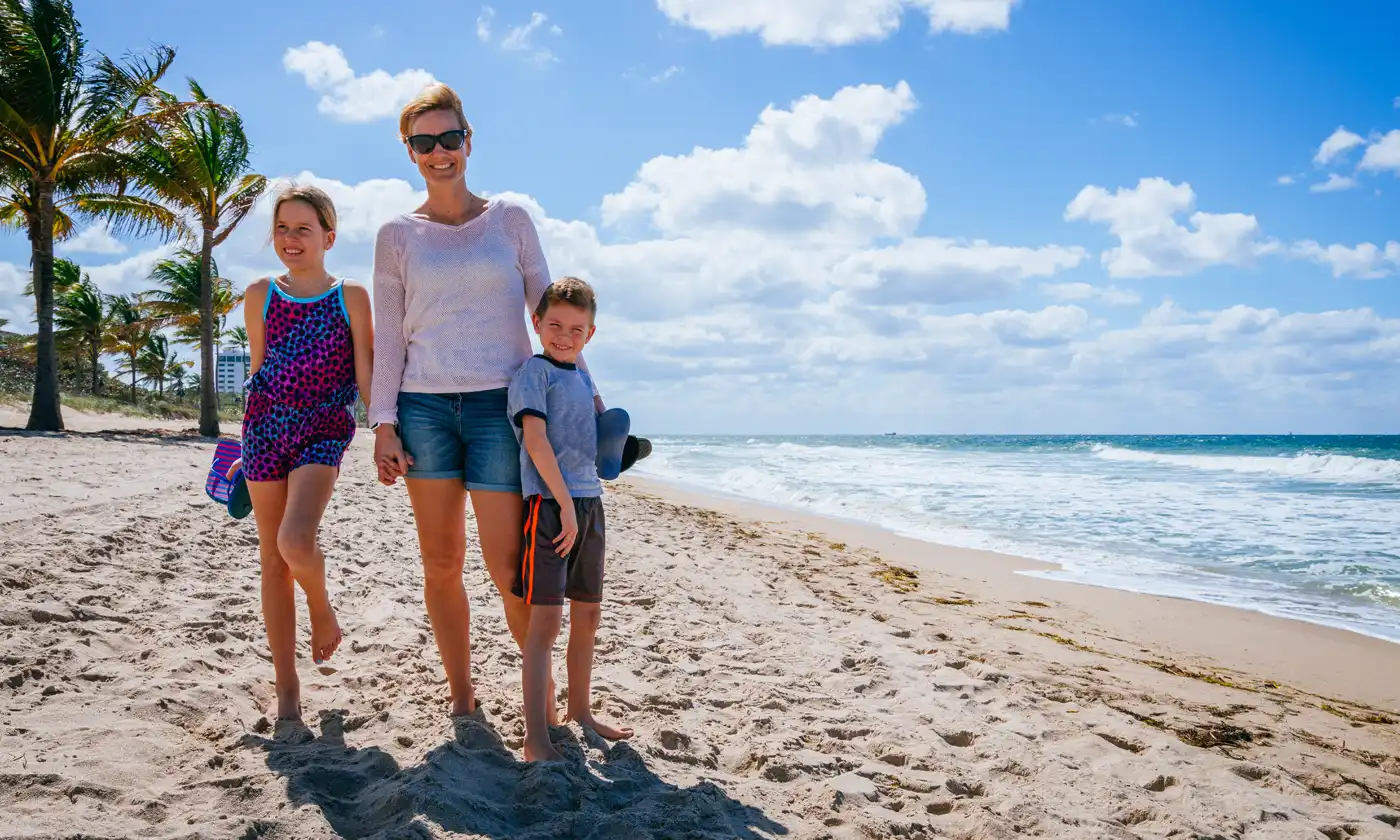 Mother walking with her children on beaches with white sand and plam trees